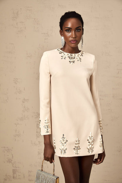 Woman wearing neutral color long sleeve mini dress with crystal embellishments