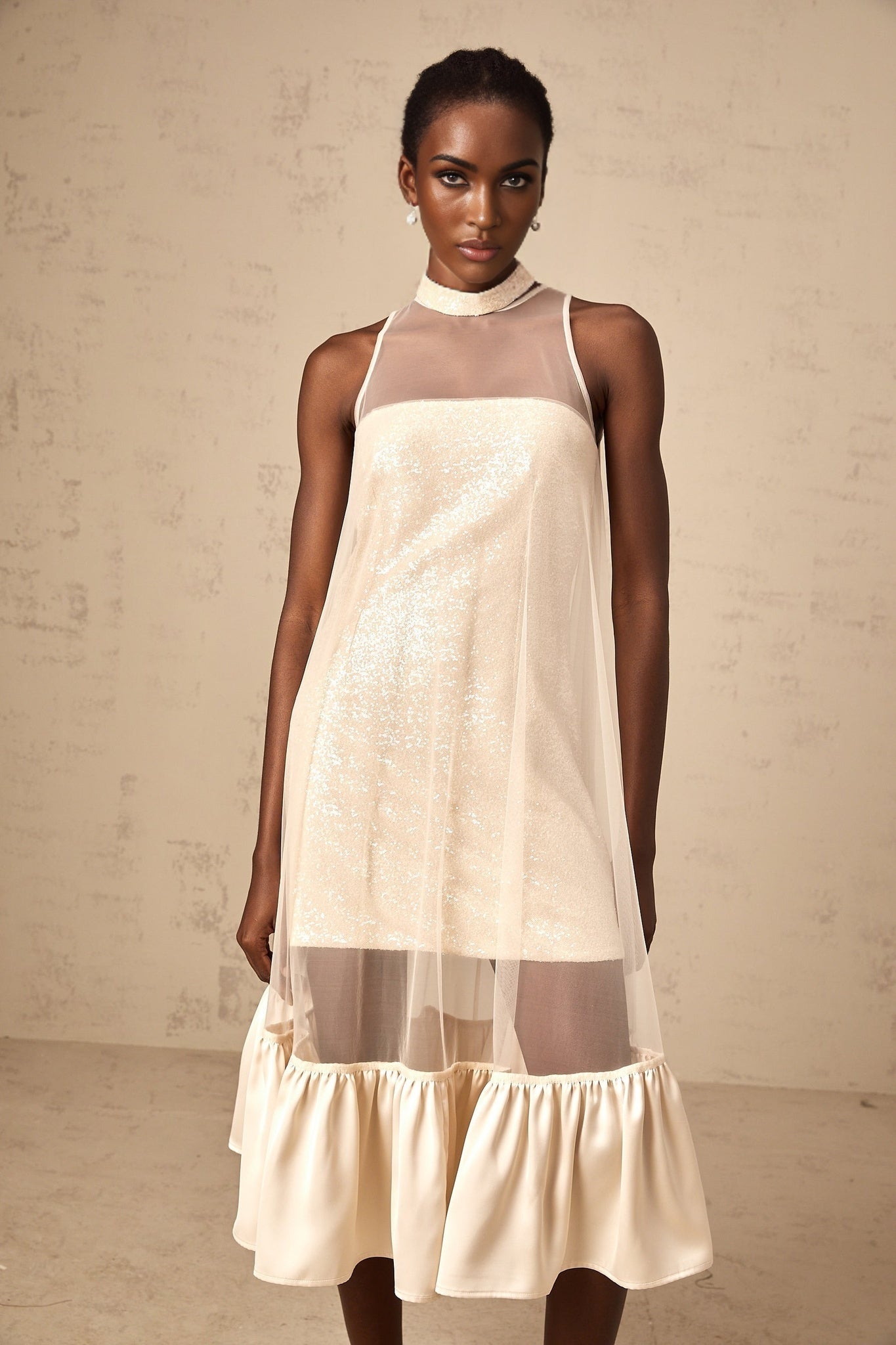 A midi dress with a layered tulle panel and sequin embellishments featuring a combination of sheer and sparkly elements in an elegant silhouette