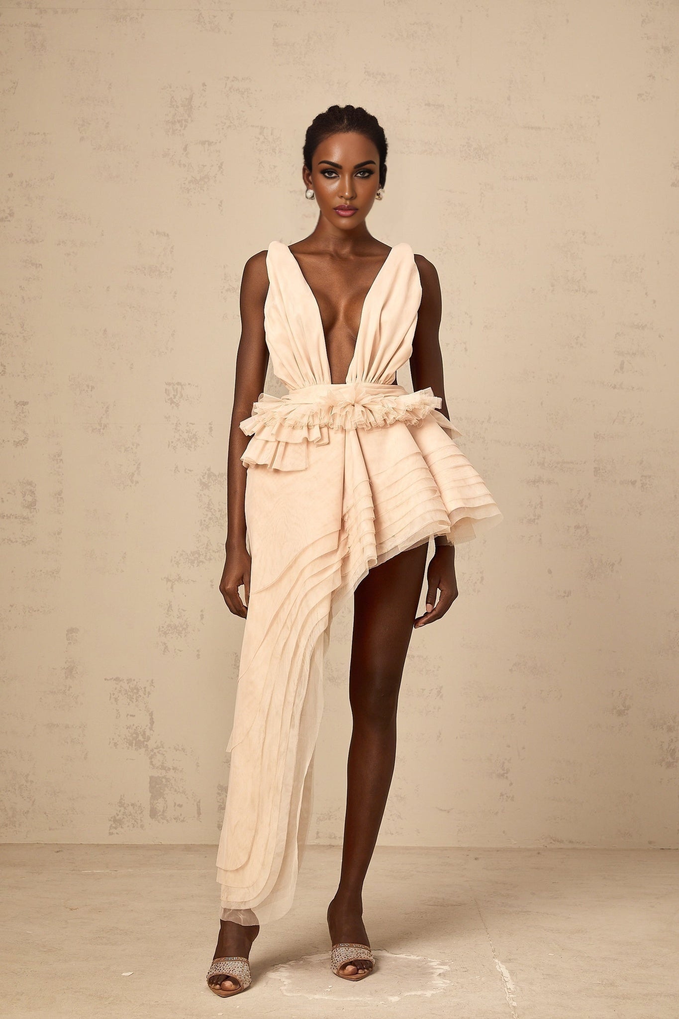 A neutral colored mini dress with an asymmetric hemline featuring a ribbon design detail