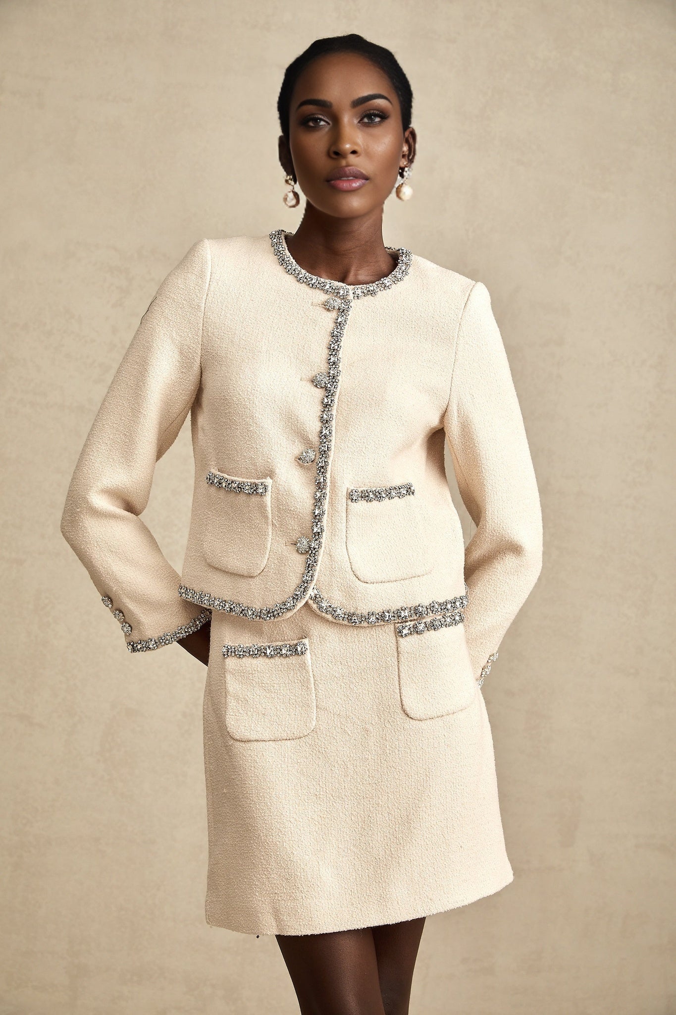 Woman wearing beige tweed cardigan and matching skirt set with crystal embellishments