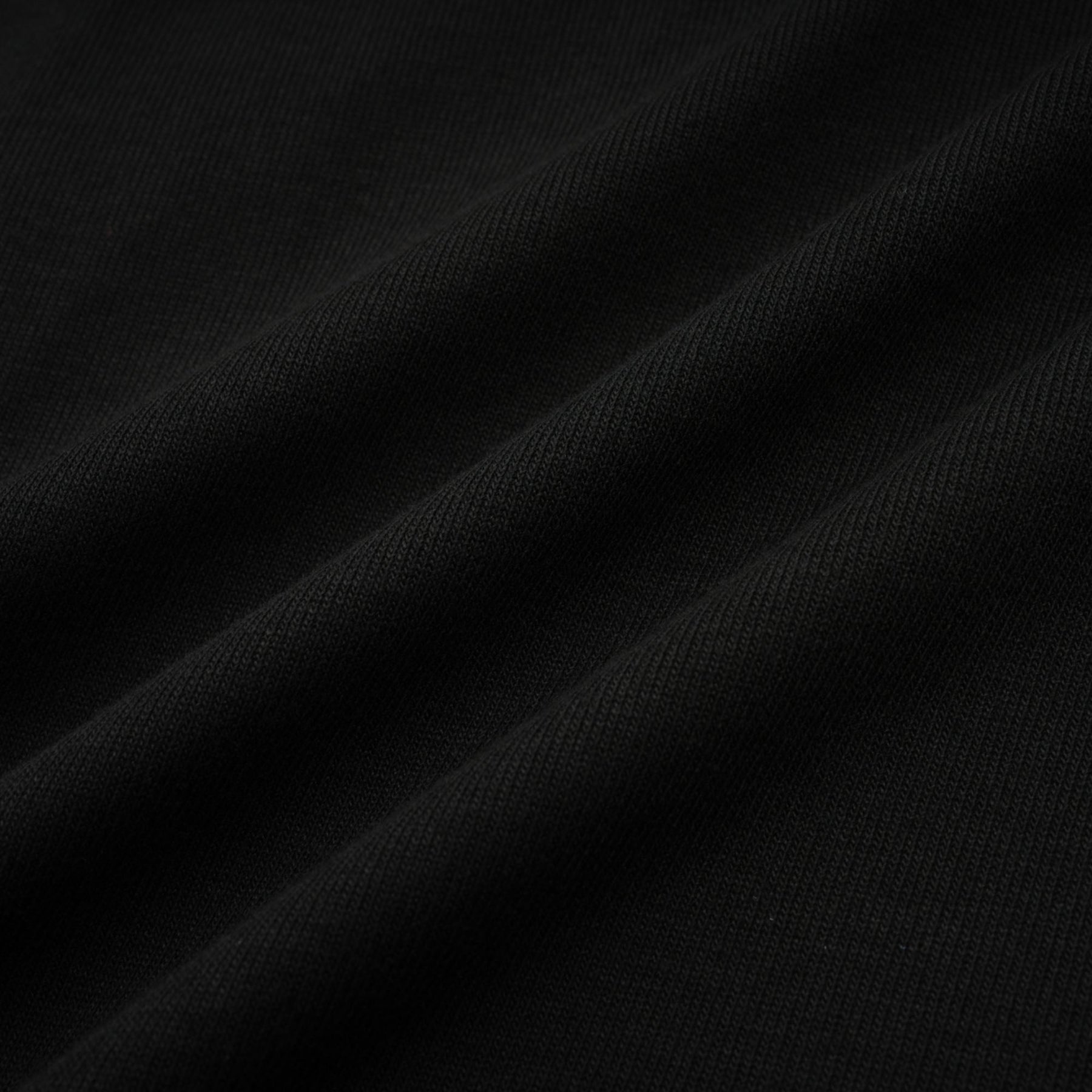 Woman wearing a black long sleeve top with ruched detailing on the sides