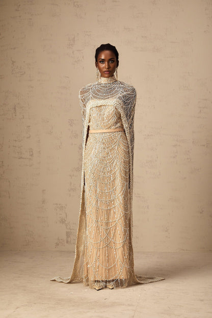 Woman wearing a champagne colored beaded gown with matching cape