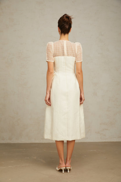 A white midi dress with braided panelling and a fitted silhouette featuring a round neckline and sleeveless design