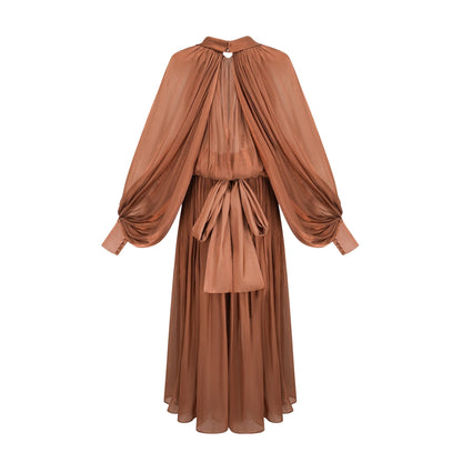 Woman wearing long brown pleated satin maxi dress with flowing skirt and fitted bodice
