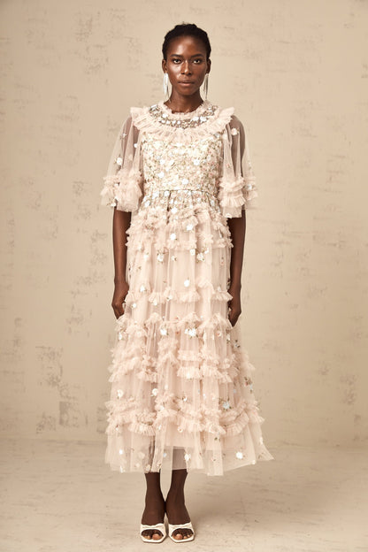 A woman wearing a midi dress with floral embroidery and tiered ruffles