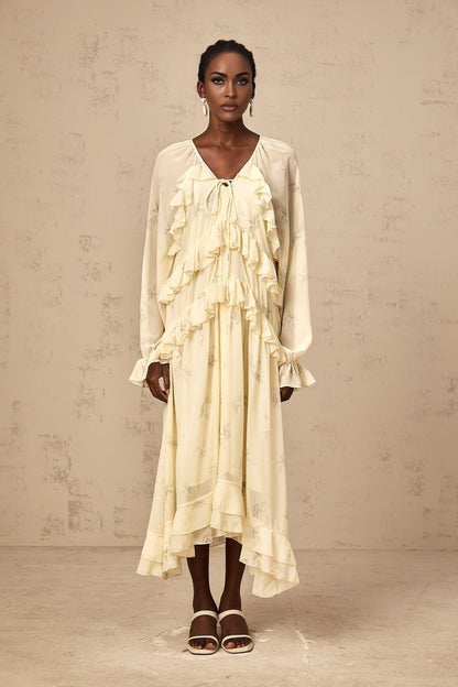 A yellow midi dress with a floral print pattern made of chiffon fabric featuring ruffle details and a flowing silhouette