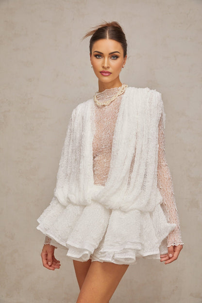 Woman wearing white lace matching set consisting of top shorts and dress Semi sheer fabric with floral lace pattern Elegant summer outfit