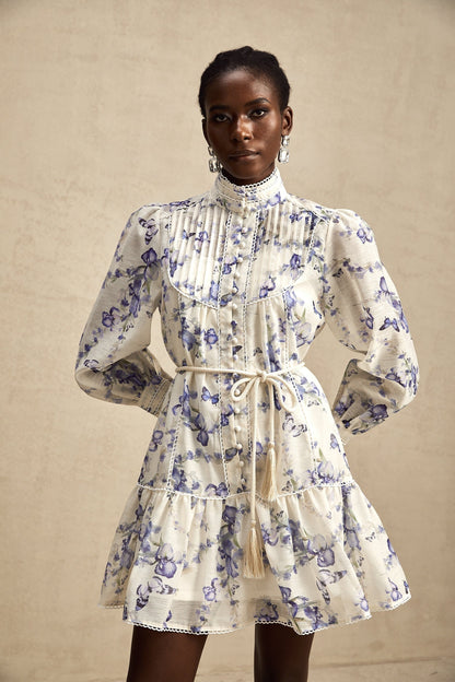 Woman wearing a short flared chiffon dress with a floral print pattern and flowing sleeves