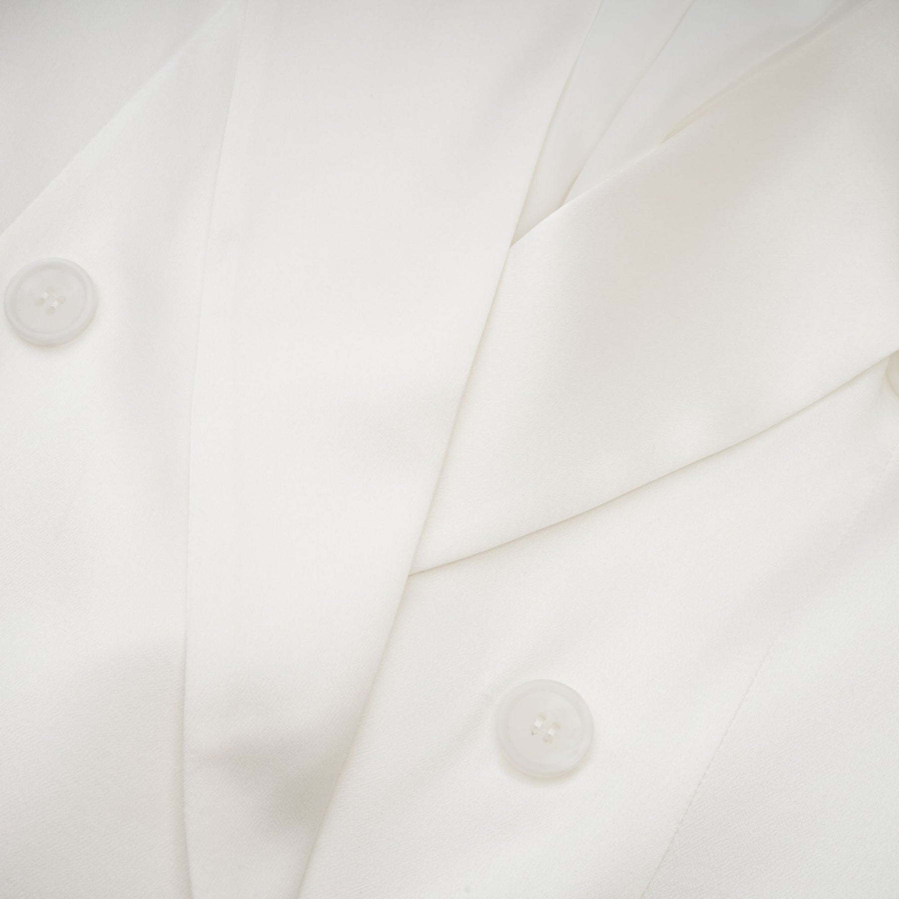 A white doublebreasted blazer named Sylvie worn by a model against a plain background
