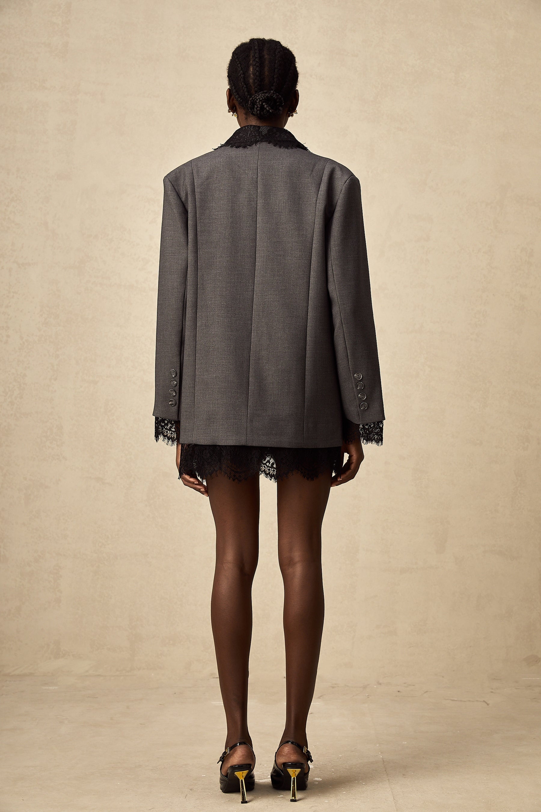 Woman wearing a grey blazer with lace panels on the sides and sleeves