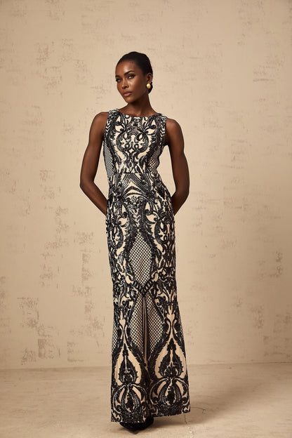 A long flowing maxi dress with sheer mesh fabric adorned with sparkling sequins in a feminine silhouette