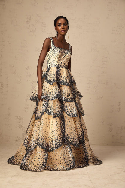 Woman wearing a long tiered maxi dress with sequined petal details and a flowing silhouette