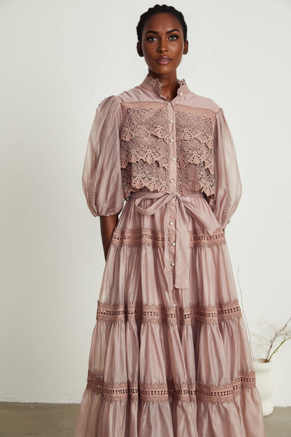 A tiered midi dress with lace detailing and cut out sections featuring a feminine silhouette in a soft color palette