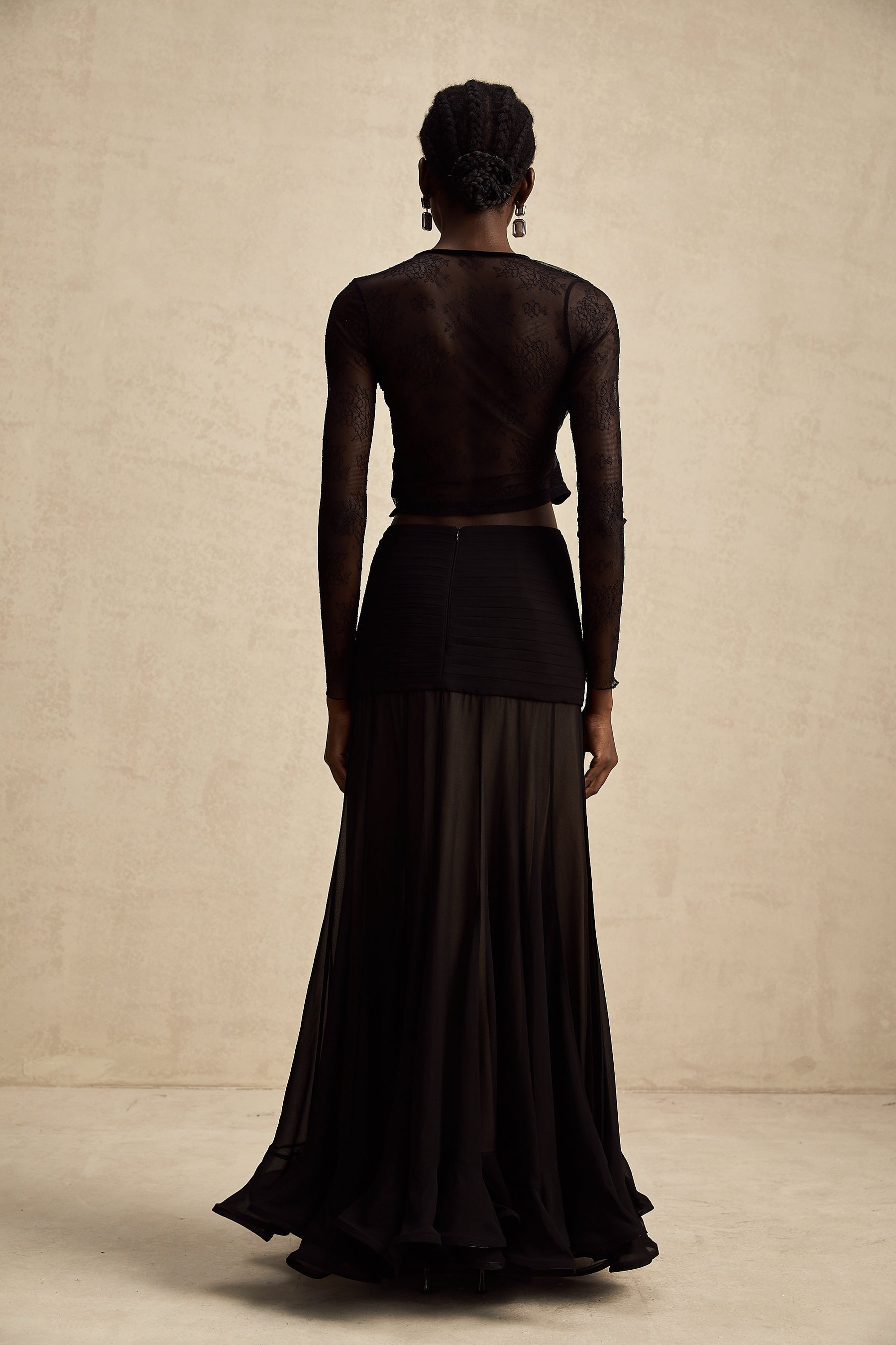 A black cropped top with sheer lace trim and see through details worn by a model