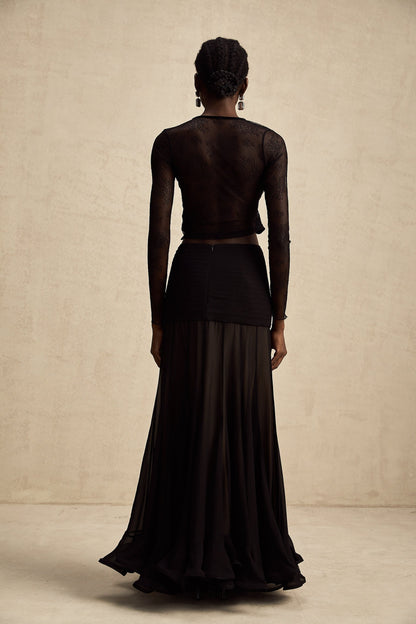 A black cropped top with sheer lace trim and see through details worn by a model