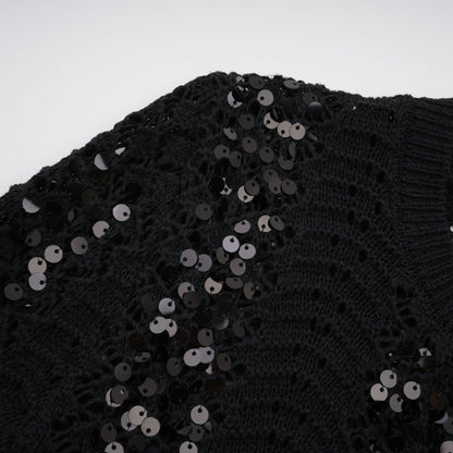 Woman wearing black sequined matching set with crochet knit cardigan and skirt