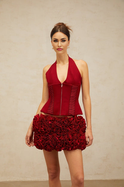 A woman wearing a bright red halterneck top with laceup detail at the front