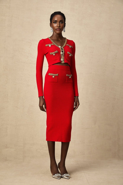 A woman wearing a matching red knitted cardigan and skirt set The cardigan features embellishments and the outfit is called Axelle