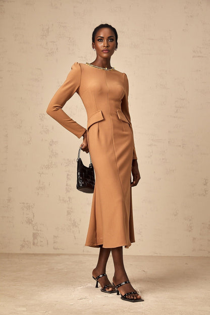 Woman wearing a khaki colored midi dress with sequin embellishments shimmering in the light