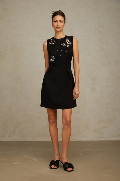 A black mini dress with sequin embellishments featuring a butterfly design worn by a model against a plain background