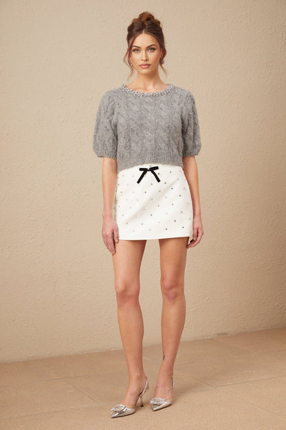 Woman wearing a cropped cable knit sweater in mohair fabric with embellishments and short length named Ophelie