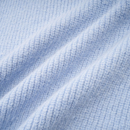 Woman wearing a blue knit blouse and matching skirt set standing in a neutral background