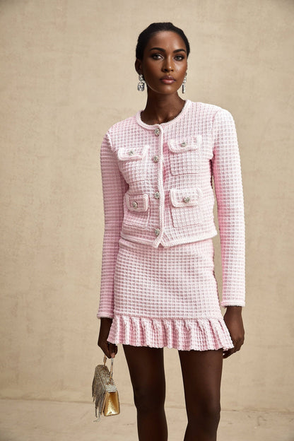 A pink waffle knit jacket and matching skirt set called Fabienne The outfit features a textured fabric in a soft pink color