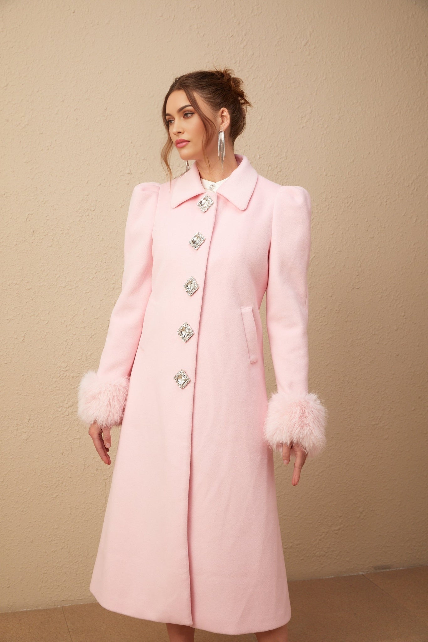 A pink faux fur overcoat named Louisette hanging on a clothing rack