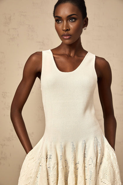 Woman wearing short white textured knit dress with floral pattern and long sleeves