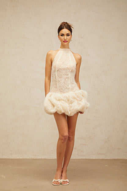 Woman wearing short beige textured mini dress with puff sleeves and gathered fabric detail