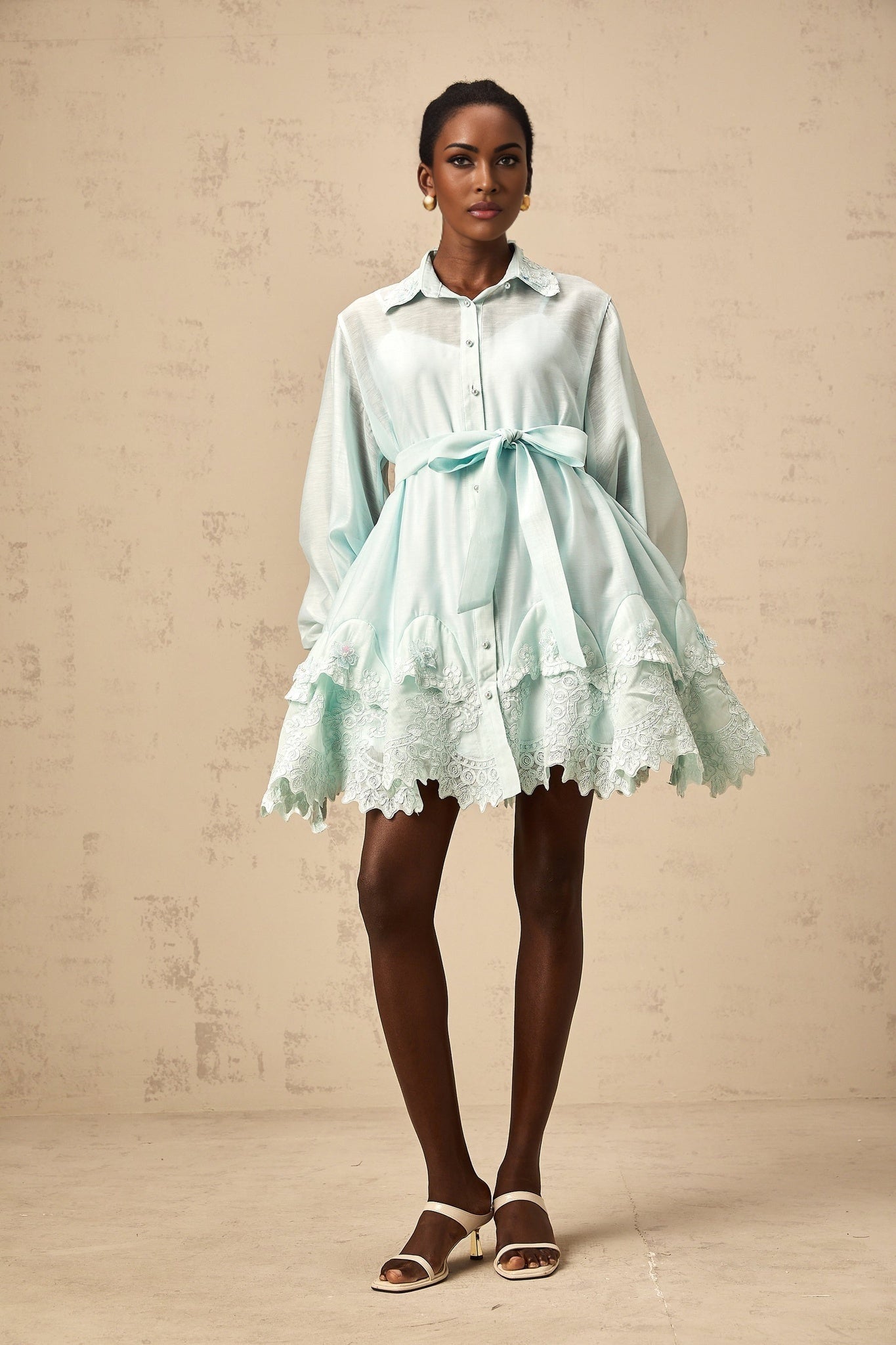 Woman wearing short green dress with lace panels and shirt collar style
