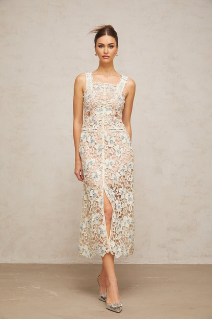 Woman wearing white Aline midi dress with floral lace pattern standing in neutral background
