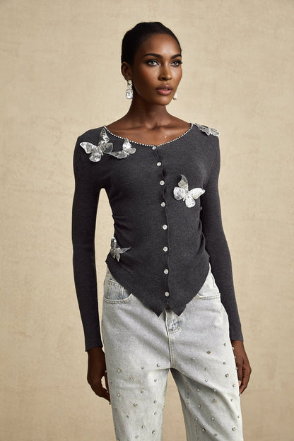 A grey cardigan with sequined butterfly designs adorning the fabric featuring long sleeves and a button front closure