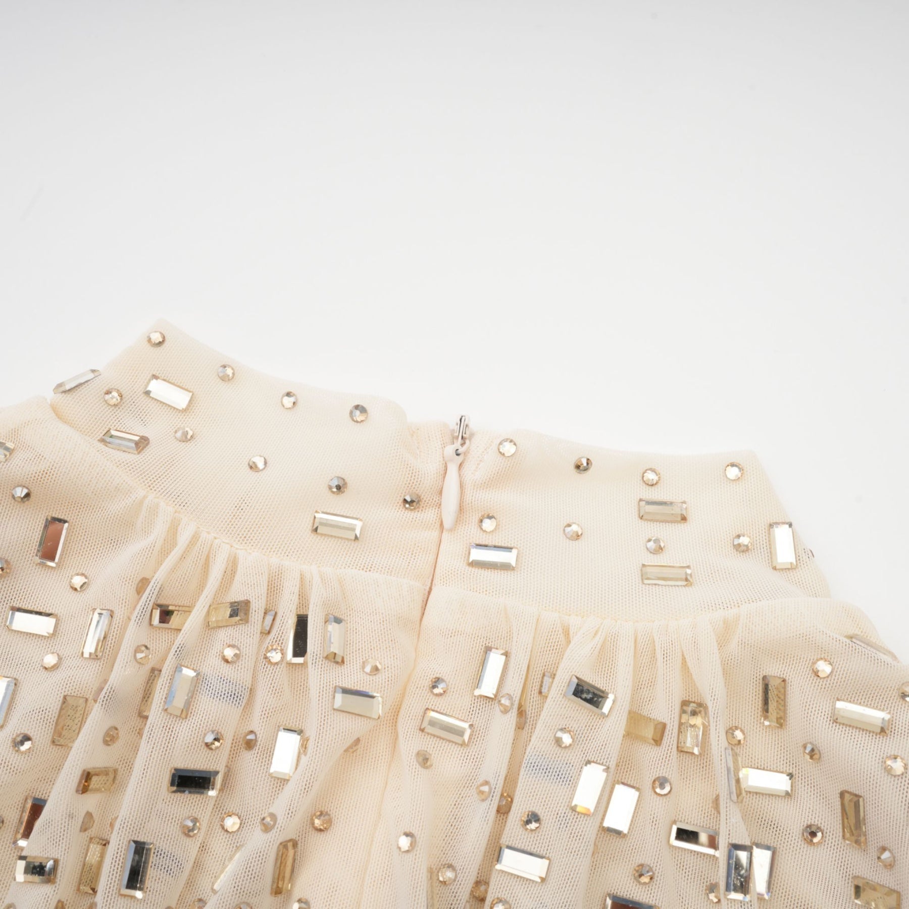 A short sleeveless mini dress with crystal embellishments and draped fabric detailing