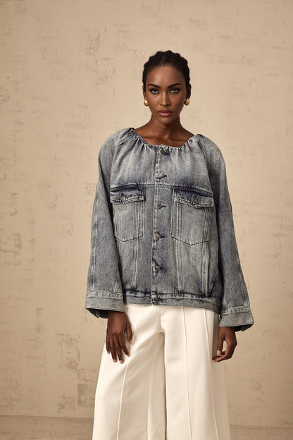 Woman wearing light blue collarless denim jacket with front pockets and button closure