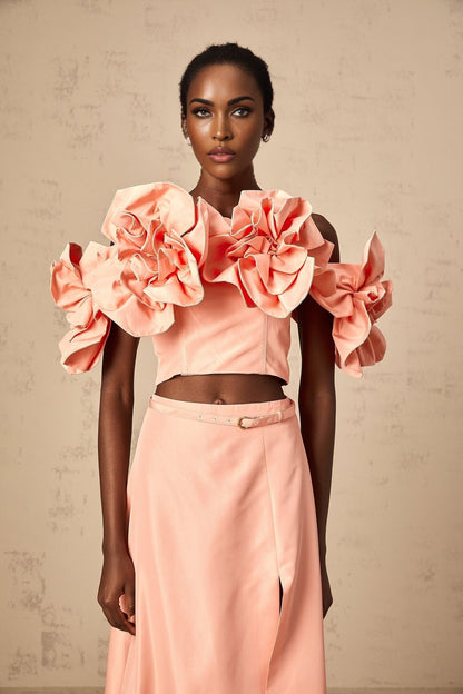 A pink twopiece outfit featuring a top and skirt with floral applique details matching set by Yvette