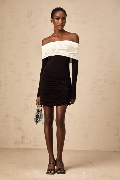 Woman wearing a fitted mini dress with colorblocked design and ruched details