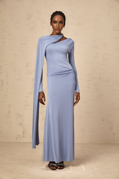 A woman wearing a long blue maxi dress with a fitted silhouette and diagonal shawl neckline
