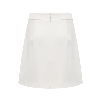 Woman wearing white twopiece outfit with crystal embellishments consisting of a sleeveless top and matching skirt