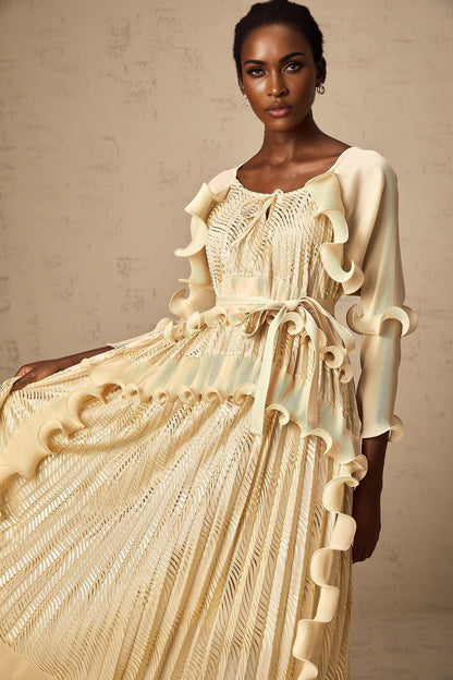 Woman wearing a neutral colored midi dress with gilded ruffles and ruffle details