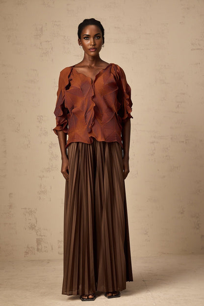 Woman wearing a demi brown matching set with creased texture top and skirt standing against plain background