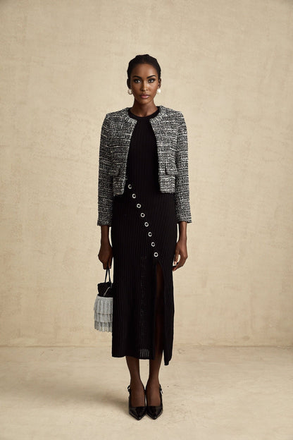 A black bouclé tweed jacket named Éloïse hanging on a clothing rack or mannequin showing its textured fabric and classic design