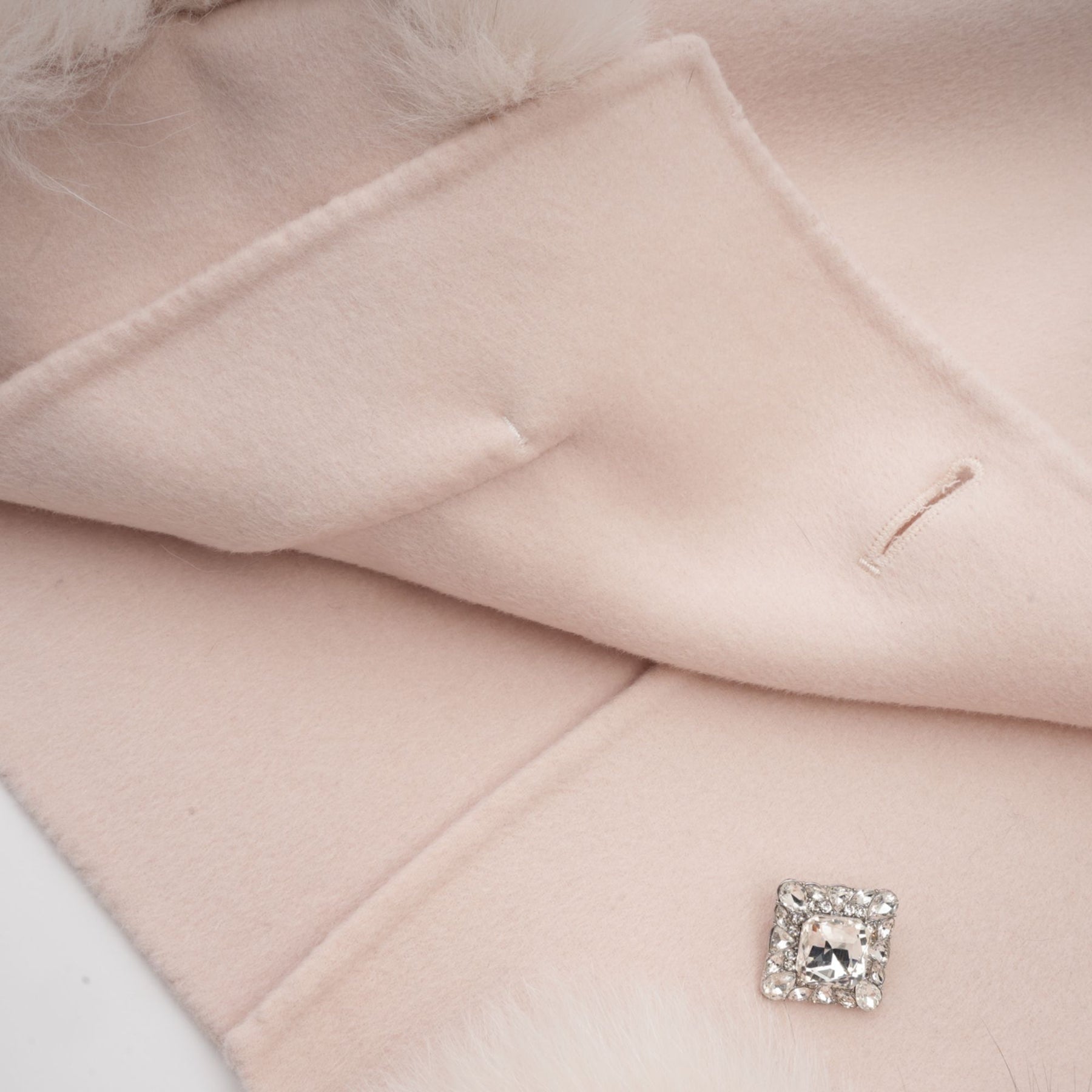 A pink short coat with a diagonal placket closure worn by a model standing against a plain background