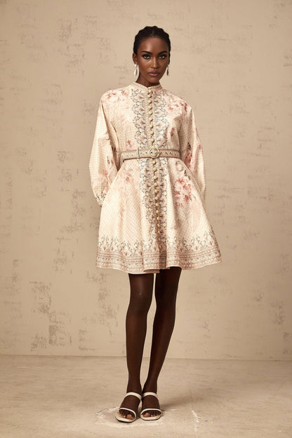 Woman wearing a short floral print dress with a belt cinching the waist