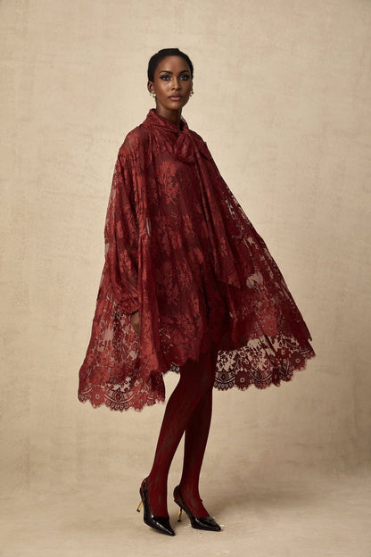 A pair of red tights with floral lace cutout patterns worn on a model showing the legs