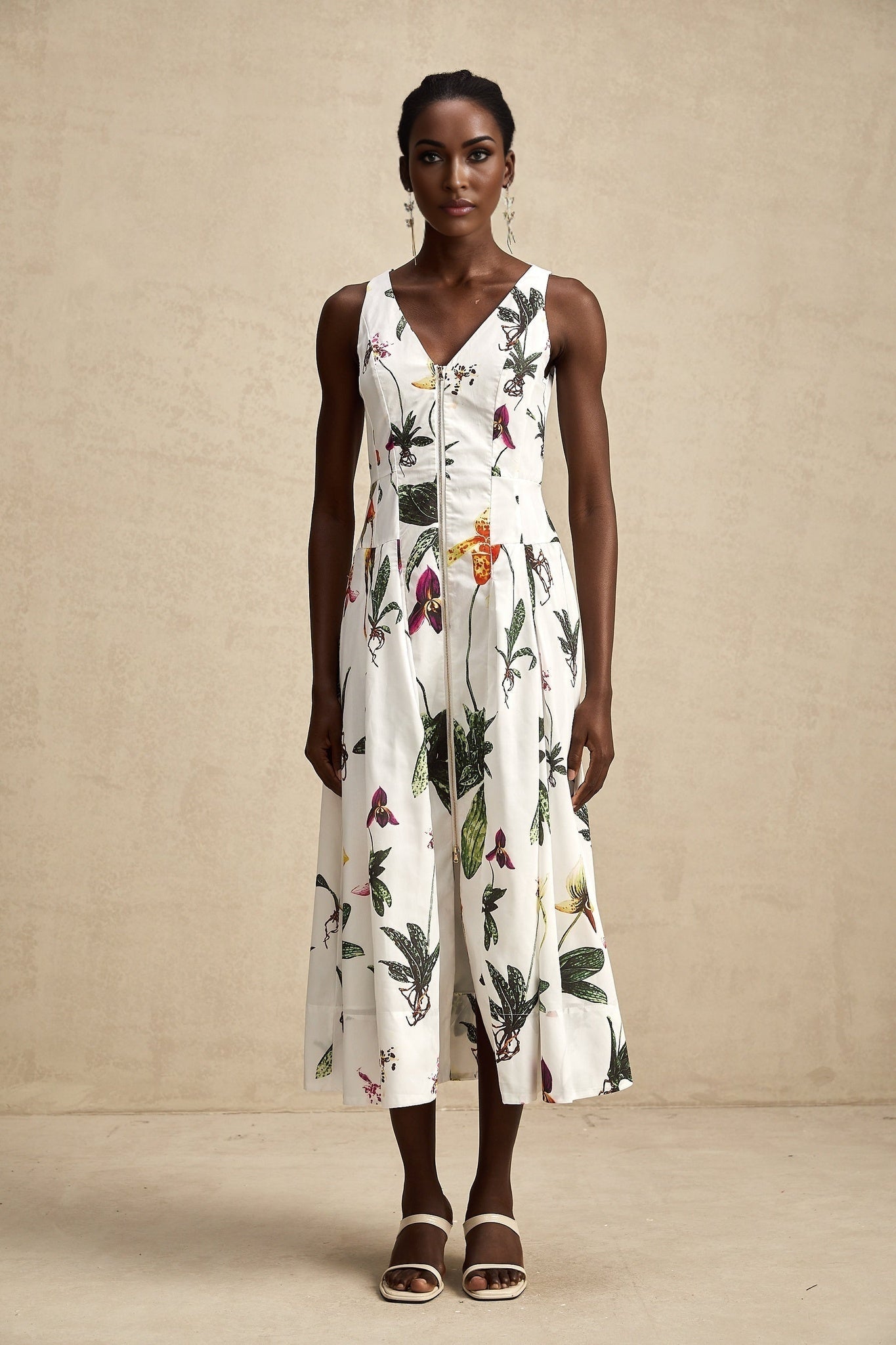 Woman wearing a floral print midi dress with vneck and poplin fabric in vibrant colors standing against a plain background