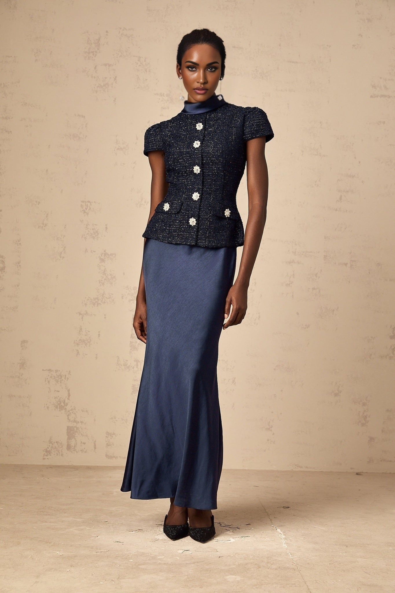 Woman wearing a long blue dress with peplum waist and panels floor length sleeveless formal gown