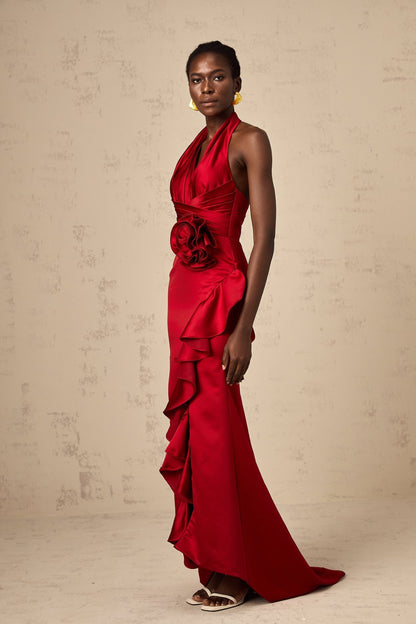 A vibrant red halterneck maxi dress with cascading 3D petal ruffles along the skirt featuring a fitted bodice and floor length design