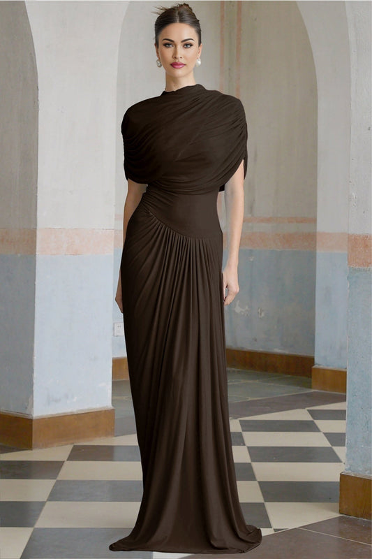 A brown asymmetric maxi dress with pleats and a flowing skirt worn by a model standing against a plain background