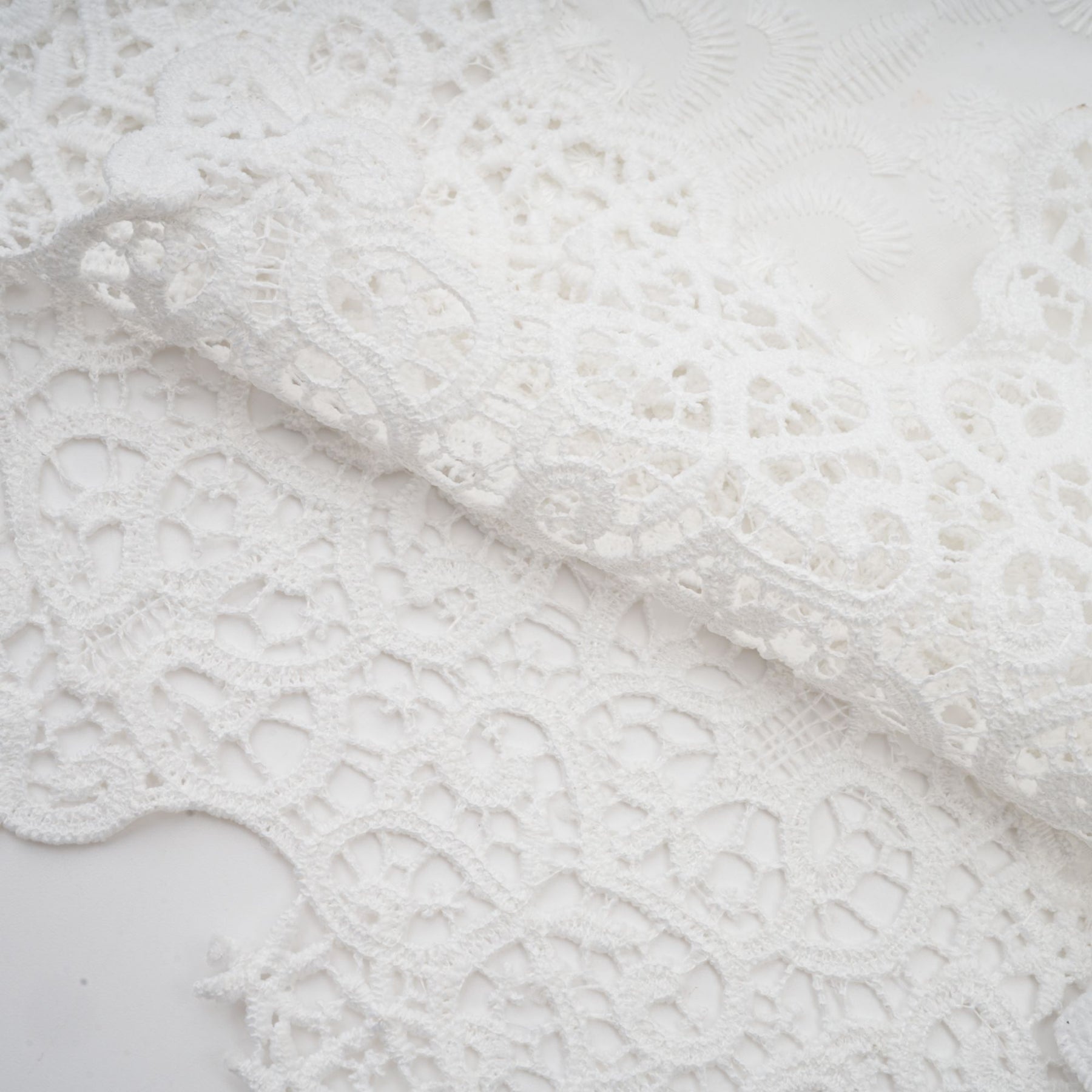 Woman wearing a matching set of white lace trimmed cropped top and trousers with cutout details